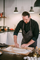 A male chef prepares noodles at home in the kitchen.