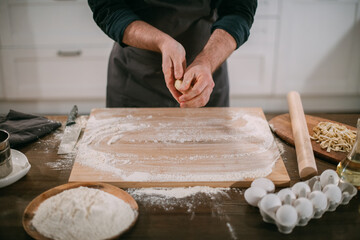 A male chef prepares noodles at home in the kitchen.