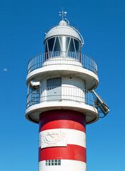 Lighthouse, against deep blue sky, with small moon. Location: Arinaga, Gran Canaria, Spain.
