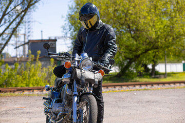 male motorcyclist with custom bobber type motorcycle outdoors in summer