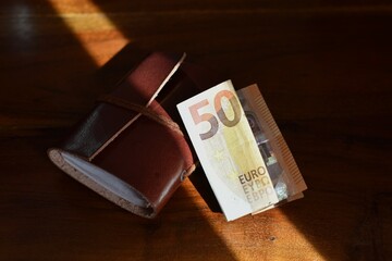 50 euro and leather bound notebook on wooden background