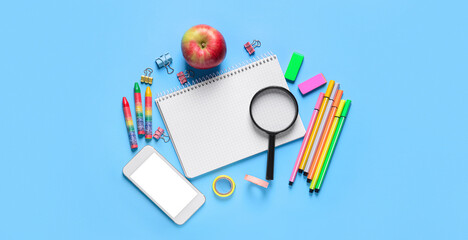 Set of school stationery with mobile phone and apple on blue background