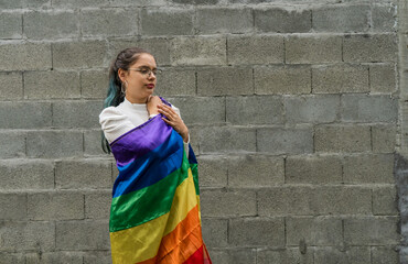 Fototapeta persona joven con la bandera del orgullo gay, joven mujer sobre fondo gris ondeando la bandera lgbtiq+ obraz