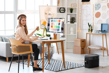 Female graphic designer with cup of coffee working at table in office