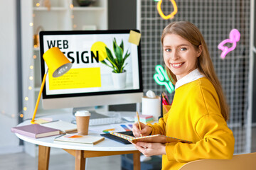 Female graphic designer working with notebook at table in office
