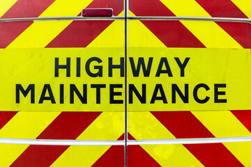 Back of a highway maintenance van with signage and bright red and yellow diagonal reflective stripes