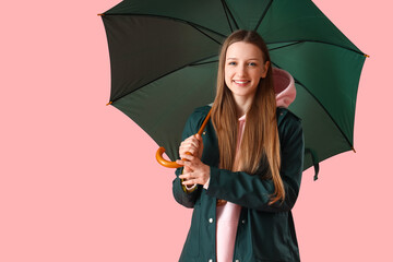 Teenage girl with green umbrella on pink background