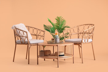 Wooden coffee table with houseplant and cozy armchairs on beige background