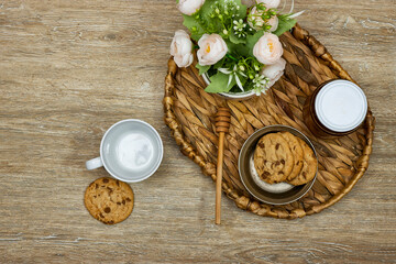 cup coffee with homemade chocolate chip cookies with honey jar and roses flowers on wood table