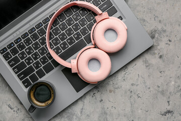 Modern pink headphones with laptop on grey grunge background