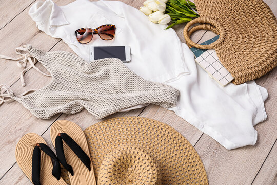 Summer clothes with accessories, mobile phone and tulips on light wooden floor