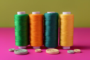 Row of thread spools and buttons on color background