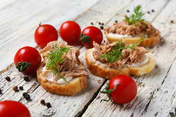 Delicious tuna bruschettas with tomatoes and peppercorn on white wooden table