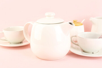Teapot and cups on pink background, closeup
