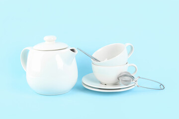 Teapot, cups and infuser on blue background