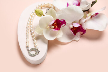 Fototapeta na wymiar Showcase pedestal with pearl necklace and orchid flowers on pink background, closeup