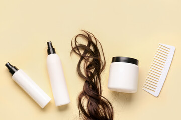 Curled brown hair with cosmetic products and comb on yellow background
