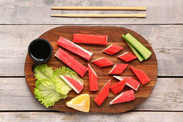 Board with tasty crab sticks and sauce on light wooden background © Pixel-Shot
