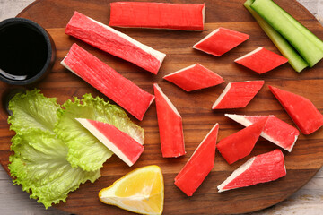 Board with tasty crab sticks and sauce on light wooden background, closeup © Pixel-Shot