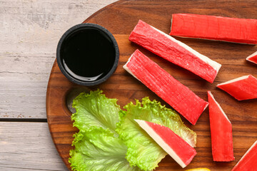 Board with tasty crab sticks and sauce on light wooden background, closeup © Pixel-Shot