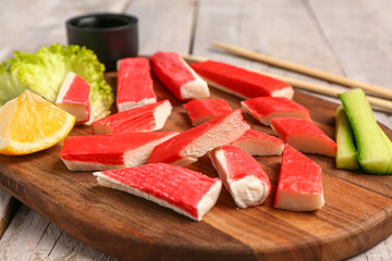 Board with tasty crab sticks on light wooden background © Pixel-Shot