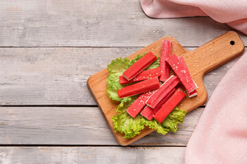 Board with tasty crab sticks on light wooden background © Pixel-Shot
