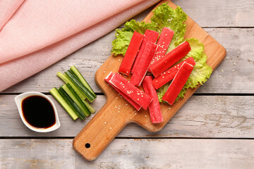 Board with tasty crab sticks and sauce on light wooden background © Pixel-Shot