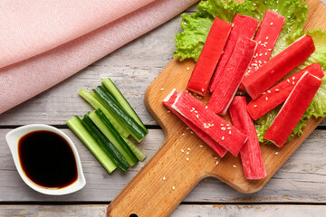 Board with tasty crab sticks and sauce on light wooden background © Pixel-Shot