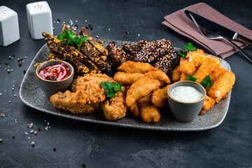 Fried rye bread croutons, chicken nuggets, chicken thighs and sauces in plate.