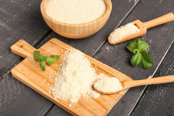 Board with tasty grated Parmesan cheese on dark wooden background