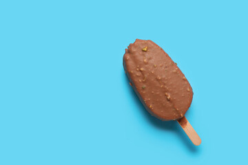 Delicious chocolate covered ice cream on stick against blue background