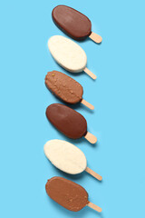 Obraz na płótnie Canvas Composition with different chocolate covered ice cream on stick against blue background