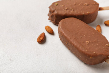Delicious chocolate covered ice cream and almond nuts on white table