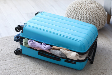 Suitcase full of clothes in living room © Pixel-Shot