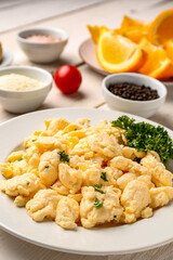 Plate of delicious scrambled eggs with ingredients on  white wooden background