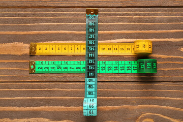 Colorful measuring tapes on wooden background