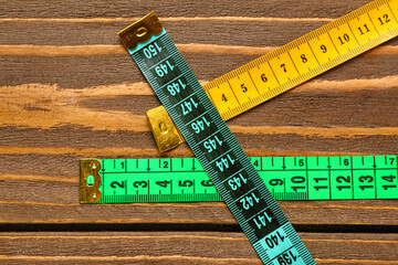 Colorful measuring tapes on wooden background