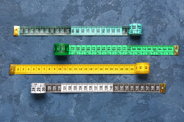 Colorful measuring tapes on blue grunge background