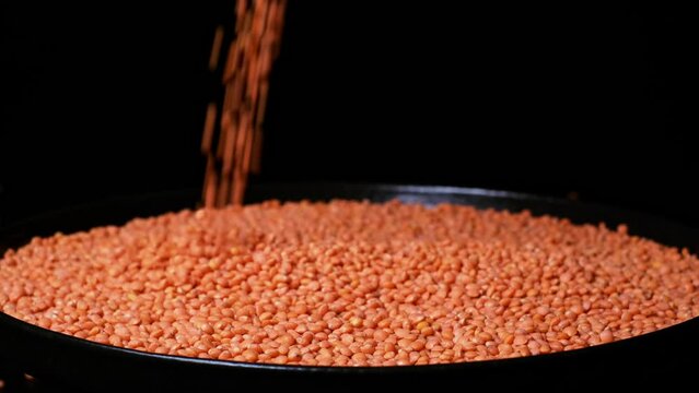 Slow motion of pouring beautiful peeled, natural dried lentils on a plate. Close-up of red lentils falling down. Organic orange coloured seeds, healthy vegan lifestyle, high protein product concept.