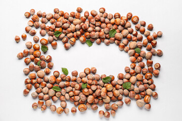 Frame made of shelled hazelnuts with leaves on grey background