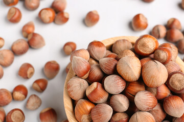 Bowl with shelled hazelnuts on light background