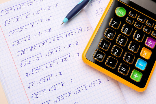 Copybook with maths formulas, calculator and pen, closeup