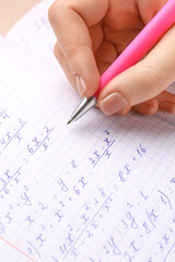 Woman writing maths formulas in copybook with pen, closeup