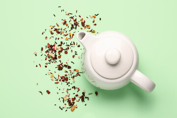 Ceramic teapot with dried fruits on green background
