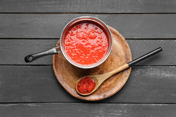 Saucepan with tasty tomato sauce on dark wooden background
