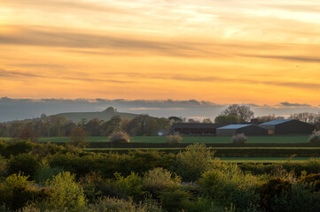 Sunset reflecting on clouds over a farm landscape