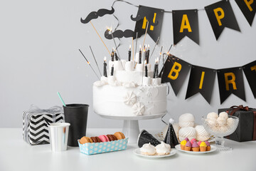 Birthday cake with different sweets on table