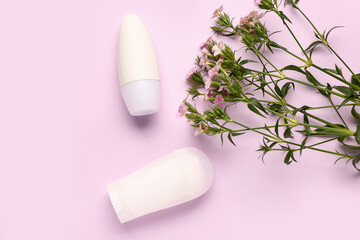 Fototapeta na wymiar Deodorants with flowers on pink background