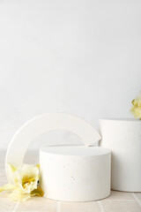 Decorative plaster podiums with daffodils on grey tile against white wall