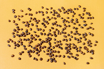 Scattered coffee beans on orange background